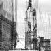 Black and white image of several people climbing fences of metal wire wearing construction clothing and helmets whilst helping each other up